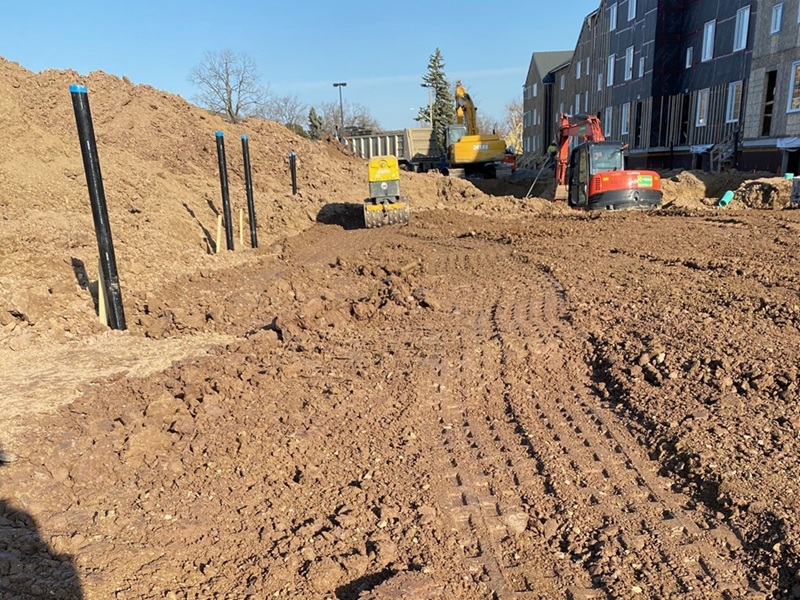 Excavators, compactor and vertical service pipes at a building construction site